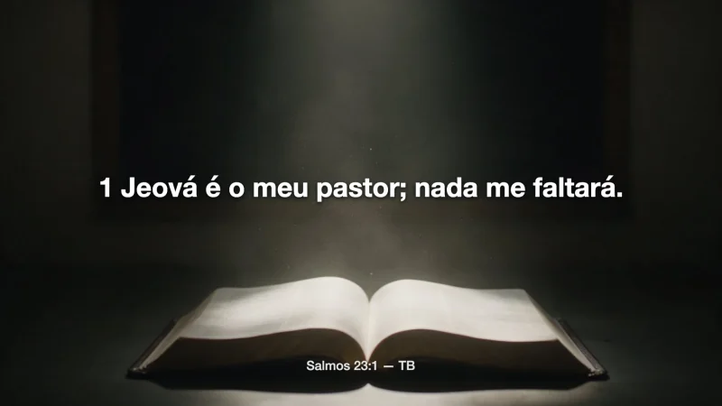 Salmos 23:1 no telão, sobre a foto de uma Bíblia aberta na luz.